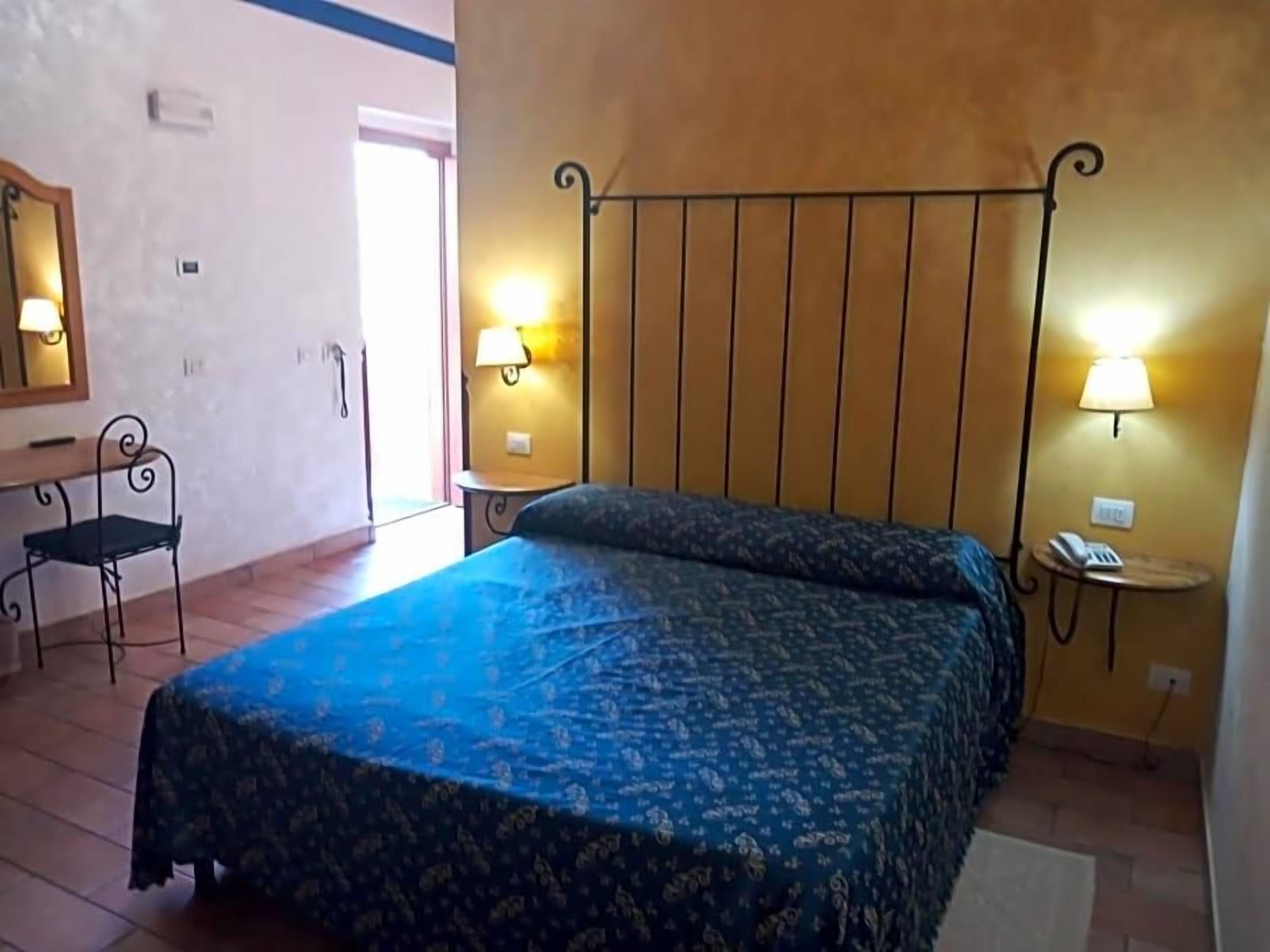 Ein Schlafzimmer mit einem Bett, zwei Nachttischlampen, einem Sessel und einem kleinen Tisch mit einem Telefon.