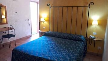 Ein Schlafzimmer mit einem Bett, zwei Nachttischlampen, einem Sessel und einem kleinen Tisch mit einem Telefon.