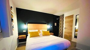 A bedroom with a bed, bedside tables, a headboard, and a door. - Hv Tel Les Chaumettes (Savines-le-Lac)