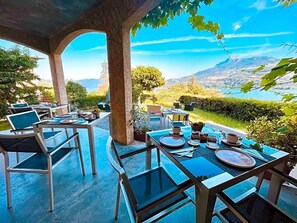 Un espace extérieur aménagé pour les repas, avec des tables et des chaises, offrant une vue sur un paysage montagneux.