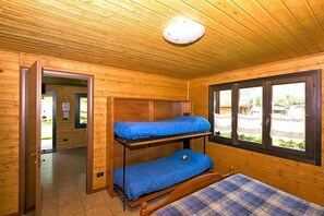Une pièce dans un chalet en bois, avec des lits superposés et une fenêtre.