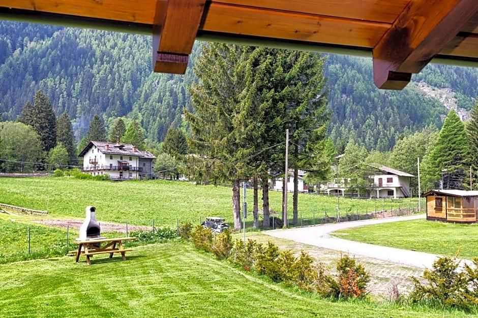 Vista de una zona rural con una estructura de madera, una mesa de picnic con una parrilla y casas al fondo.