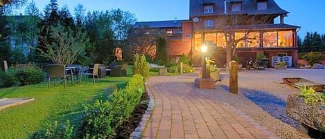 A hotel with a paved driveway leading to a building with multiple windows and a well-maintained garden.