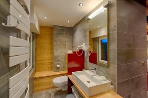 Un baño moderno con un lavamanos blanco, un inodoro y una zona de ducha.