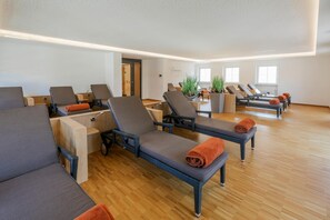 A room with multiple sun loungers, wooden flooring, and a door leading to another area. - Hotel Kurhaus Bad Bocklet (Bad Bocklet)