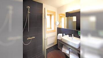Ein modernes Badezimmer mit Dusche, Waschbecken und Spiegel.