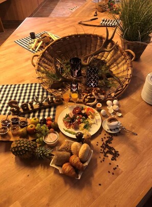 Una mesa de madera con diversos alimentos, como frutas, pan y un plato de aperitivos.