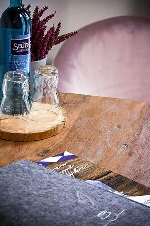 Una mesa de madera con una botella, dos vasos y un recipiente pequeño.