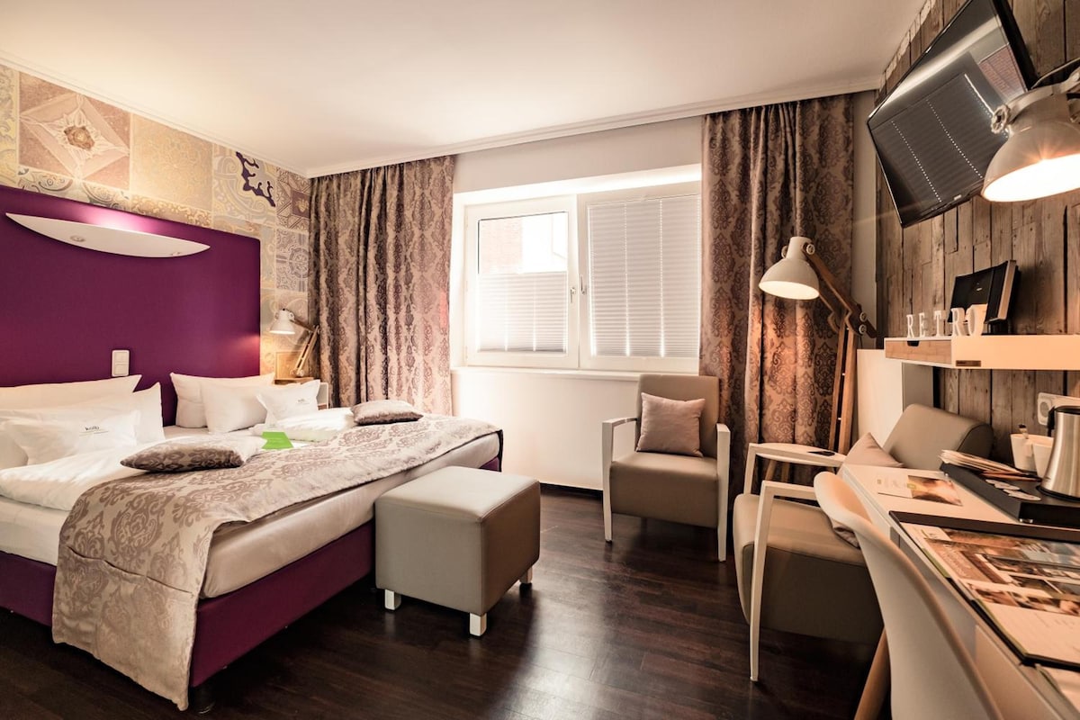 Una habitación de hotel moderna con una cama, un escritorio, una silla y un televisor.