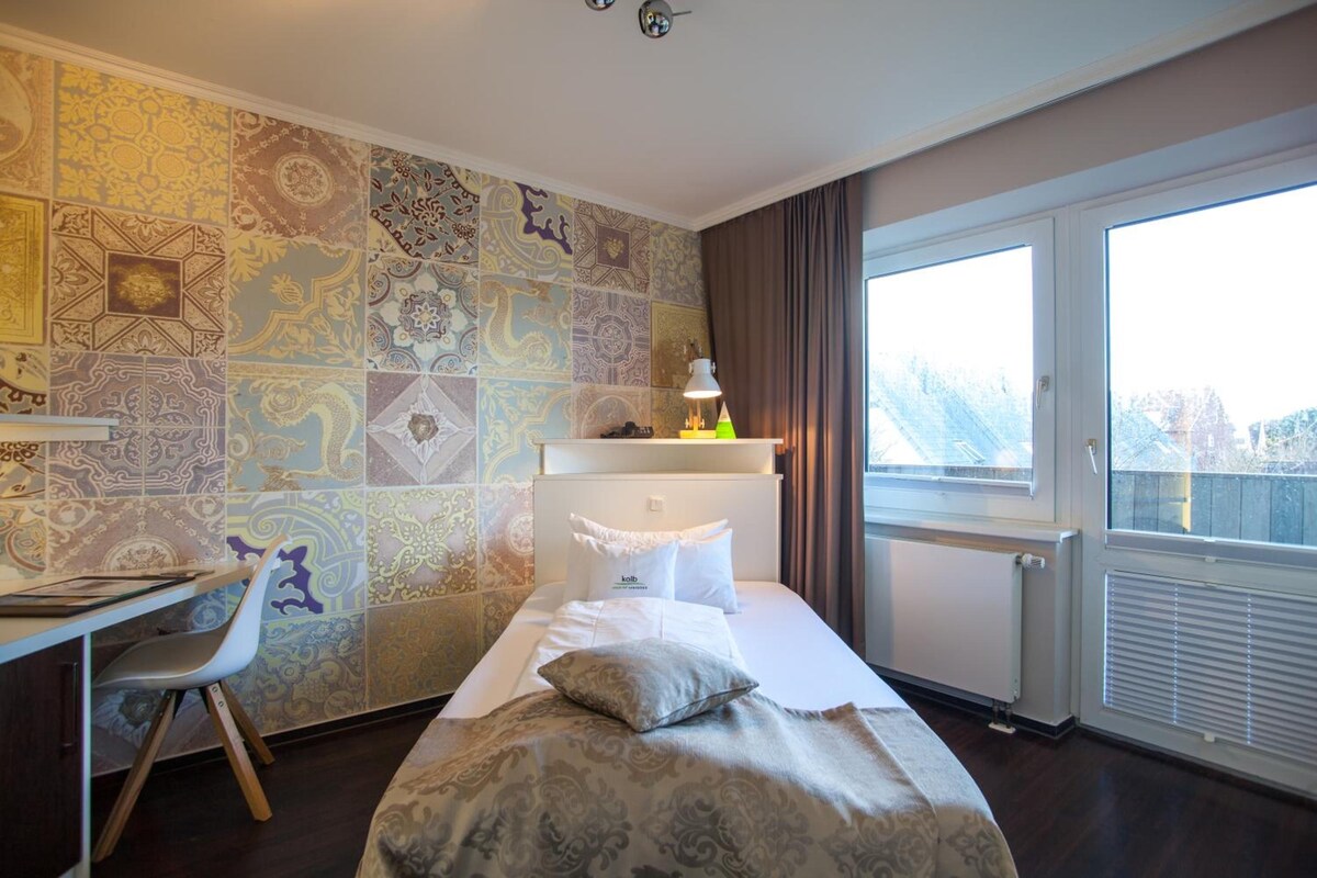 Una habitación de hotel con una cama, un escritorio, una silla y un ventanal grande.