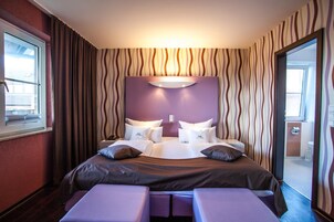 Una habitación de hotel con cama, mesita de noche, teléfono y vistas al exterior.