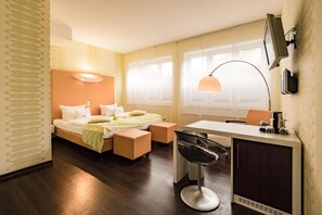 Una habitación de hotel moderna con una cama, un escritorio, una silla y un televisor.
