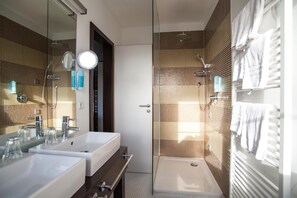 Un baño moderno con dos lavamanos, una ducha y un espejo grande.