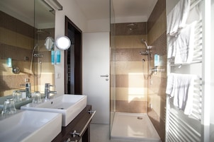 A modern bathroom with two sinks, a shower, and a large mirror.