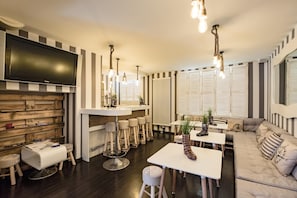 Una sala de estar moderna con un televisor de pantalla plana, paredes a rayas, una zona de bar y un sofá.