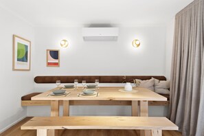 En matplats med ett träbord för fyra personer, en bänk och en soffa.