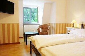 A hotel room with a bed, a chair, a table, a lamp, and a TV. - Landhotel Gut Zarrentin (Gransebieth)