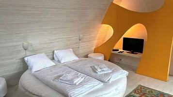 A modern bedroom with a bed, bedside tables, a television, and a unique architectural design.