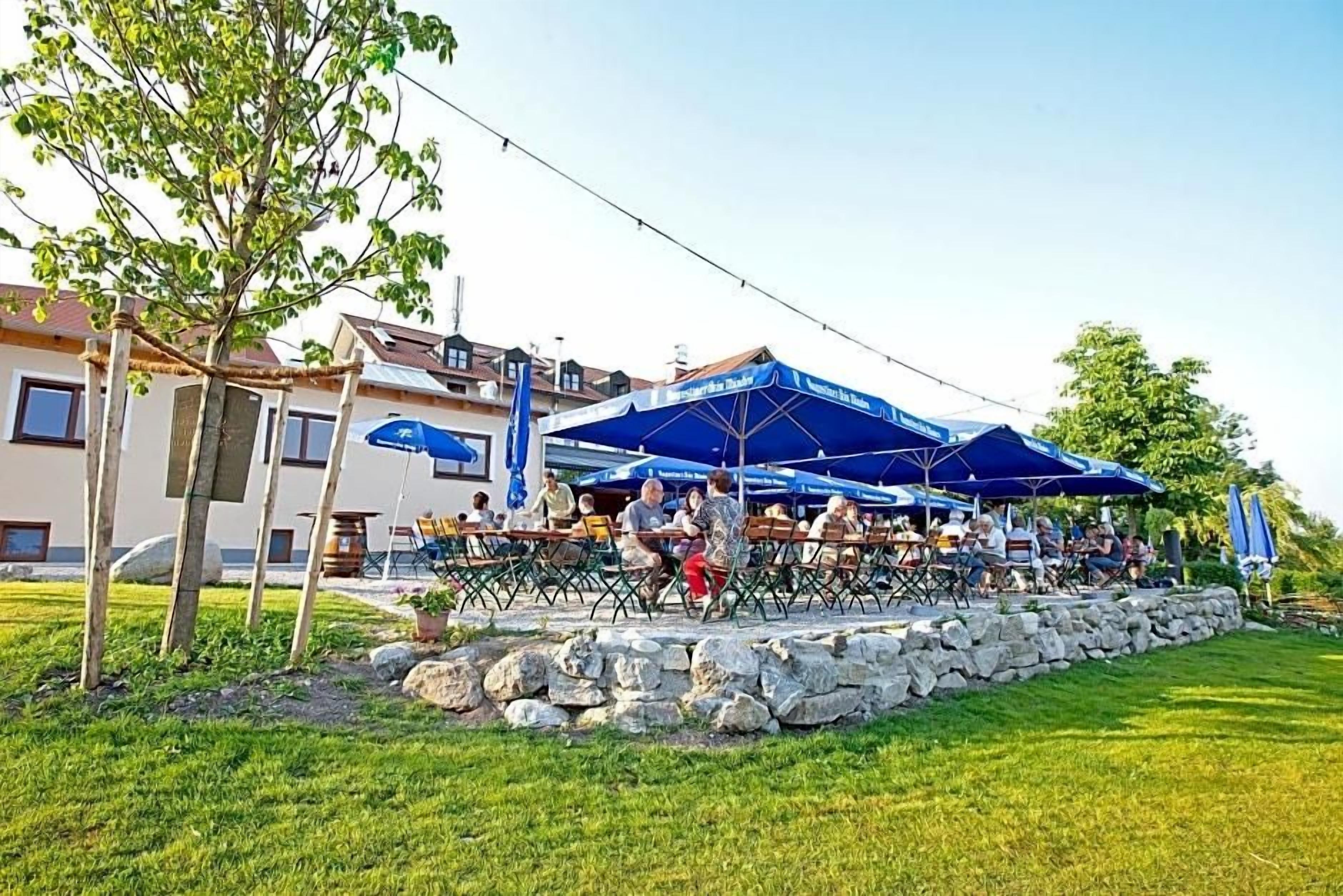 Een terras met tafels en stoelen, een stenen muur en een gebouw op de achtergrond.