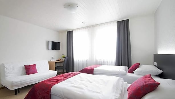 Une chambre d’hôtel avec deux lits, un bureau et une télévision.