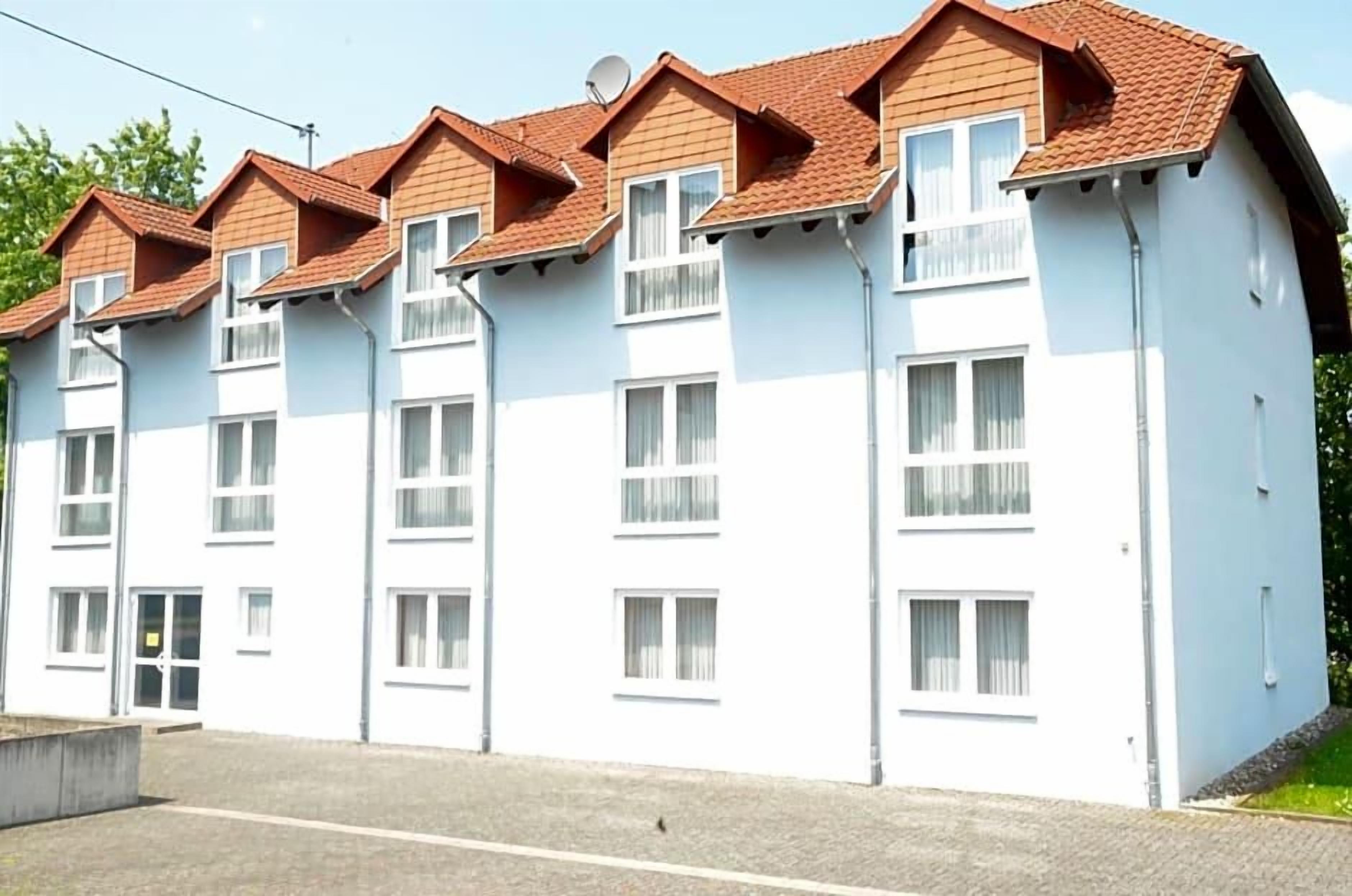 A multi-story residential building with a white facade and red-tiled roofs.