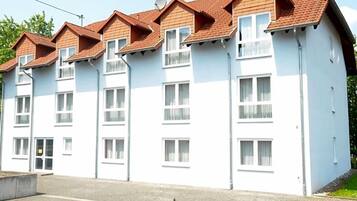 A multi-story residential building with a white facade and red-tiled roofs.