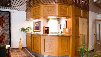 A curved wooden bar area with intricate designs, a small plant, and a framed artwork on the wall.