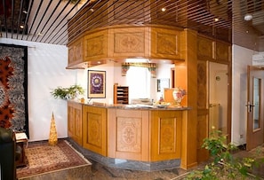 A curved wooden bar area with intricate designs, a small plant, and a framed artwork on the wall.