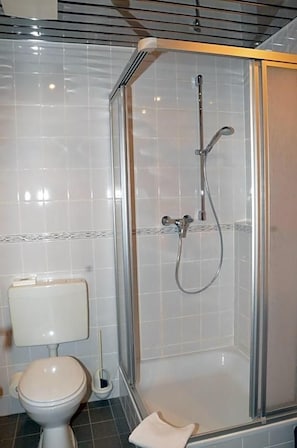 A bathroom with a glass-enclosed shower, a toilet, and a bidet.