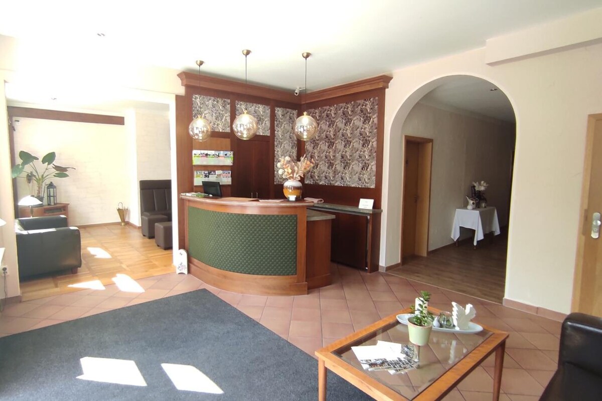 A hotel lobby with a reception desk, seating area, and a coffee table.