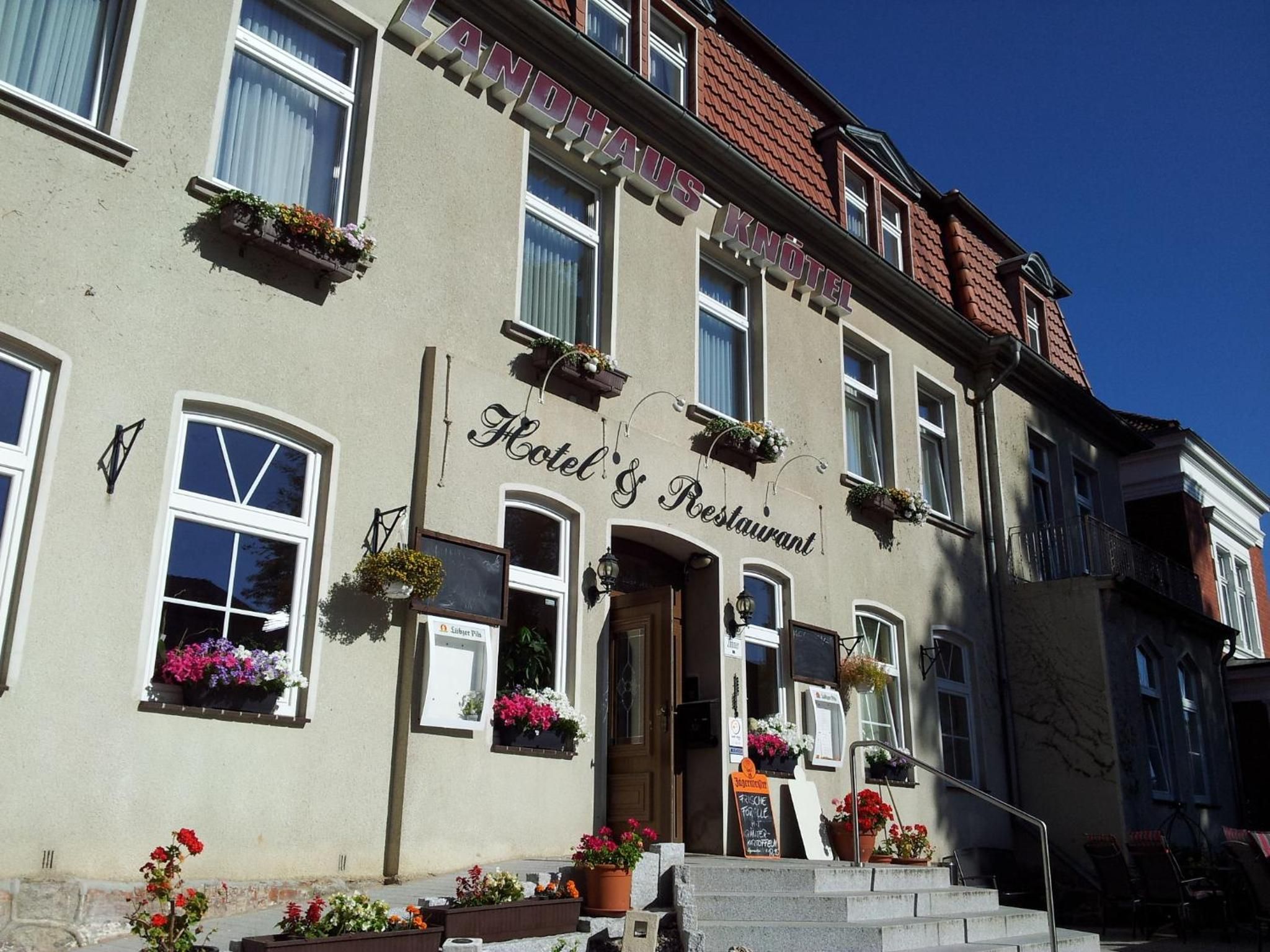 A hotel with a sign reading 'Hotel & Restaurant' and flower boxes on the windows.
