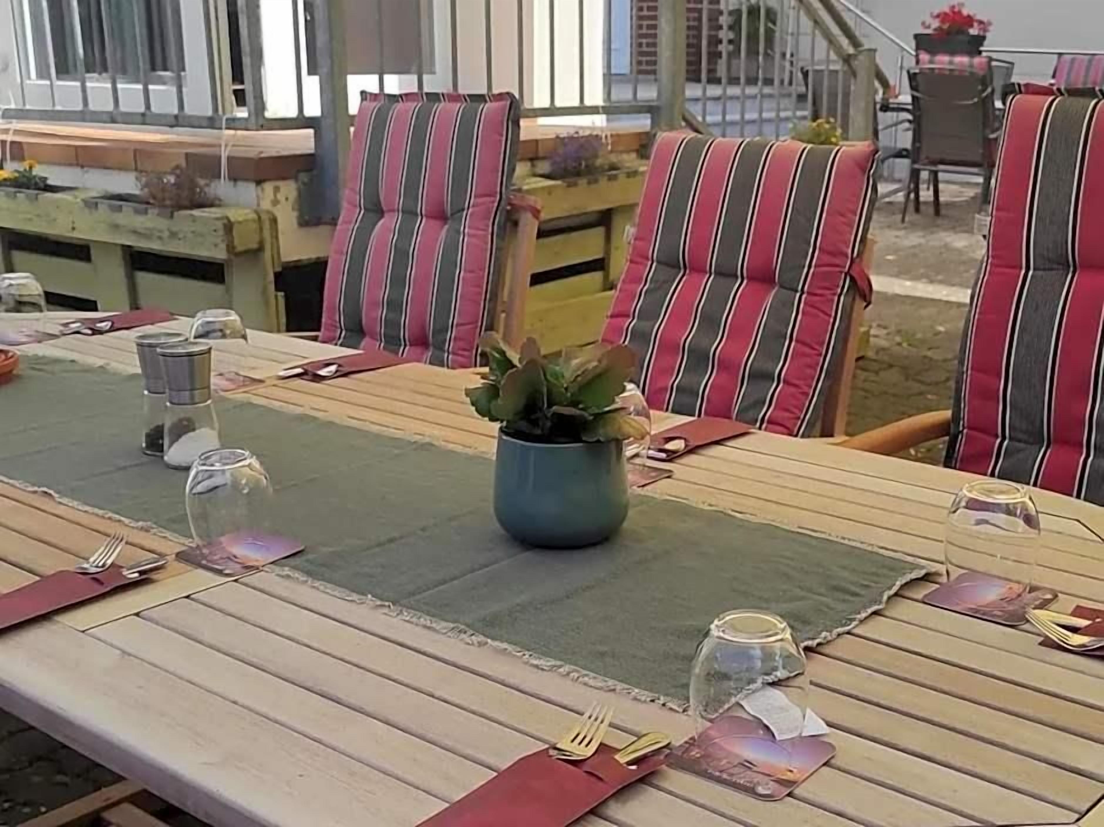 A dining table set with striped chairs, a vase with a plant, and a placemat.