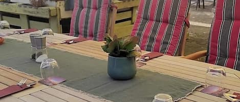 A dining table set with striped chairs, a vase with a plant, and a placemat.