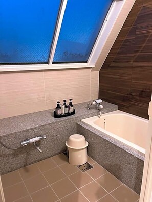 A bathroom with a skylight, a bathtub, a shower, and a toilet.