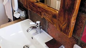 Un bagno con un lavandino bianco, uno specchio con cornice in legno e articoli da toilette sul ripiano.
