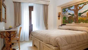 Una camera da letto con un letto, una scrivania e una sedia. Al muro, un quadro.