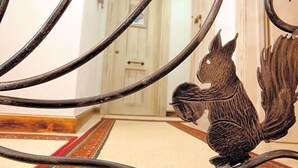 Un portail en fer forgé orné d’un motif de lion, qui donne sur une pièce dont le sol est recouvert d’un tapis rouge et beige.