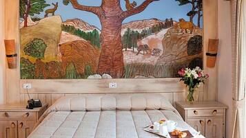 Una camera da letto con un grande affresco raffigurante una scena di foresta, un letto con un vassoio per la colazione e comodini con lampade.
