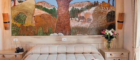 A bedroom with a large mural of a forest scene, a bed with a tray of breakfast, and bedside tables with lamps.