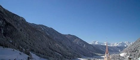 A snow-covered village with a church and buildings, surrounded by mountains.