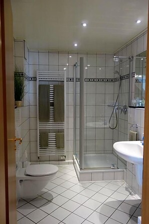 Un baño con inodoro, cabina de ducha y lavamanos.