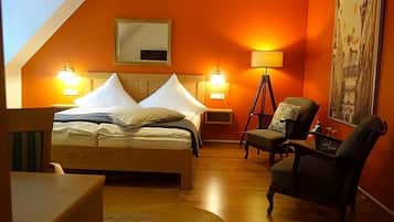 A bedroom with a bed, bedside lamps, a chair, a desk, and a painting on the wall.