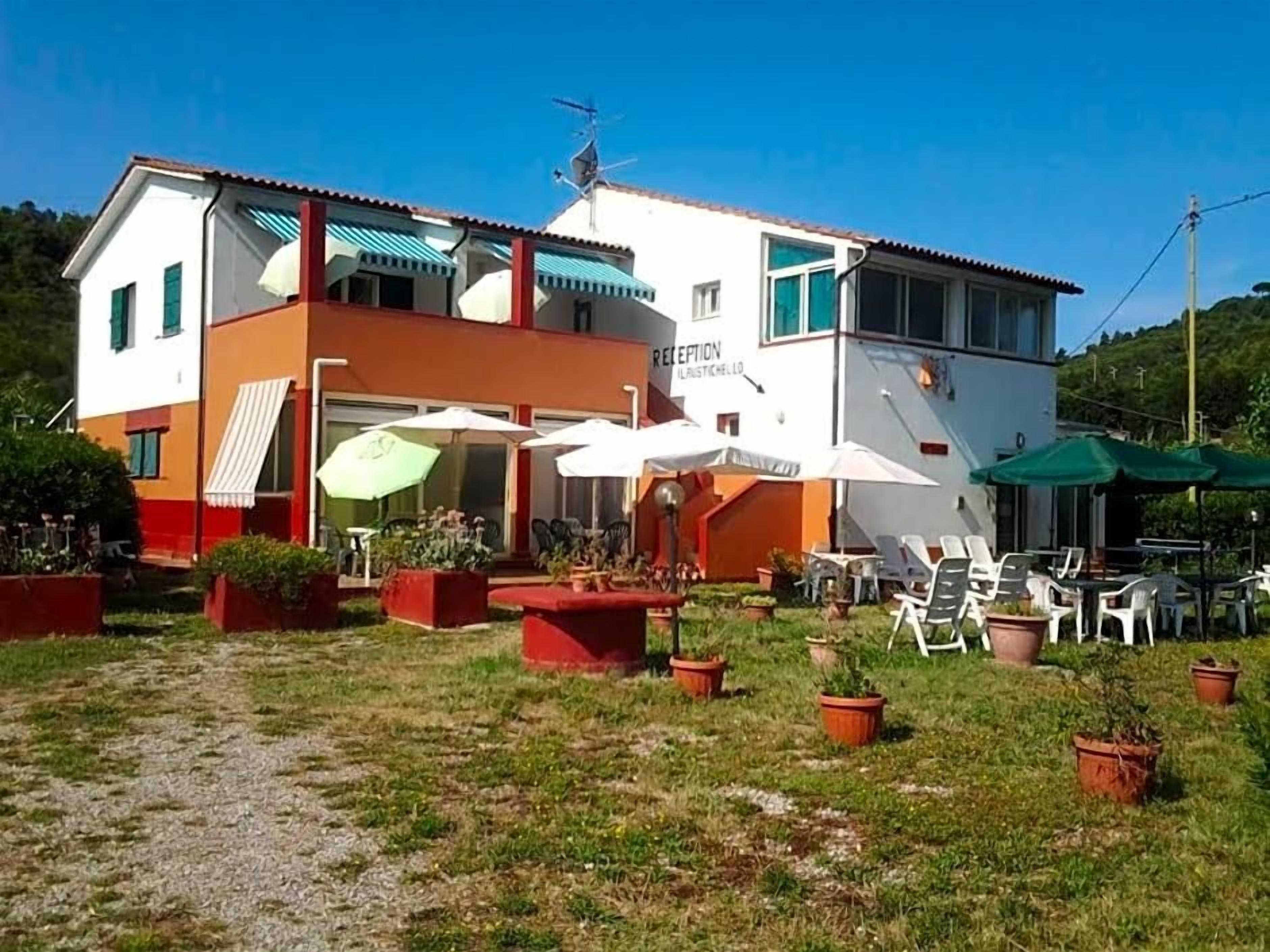 Un edificio a due piani con una reception, posti a sedere all'aperto e piante in vaso.