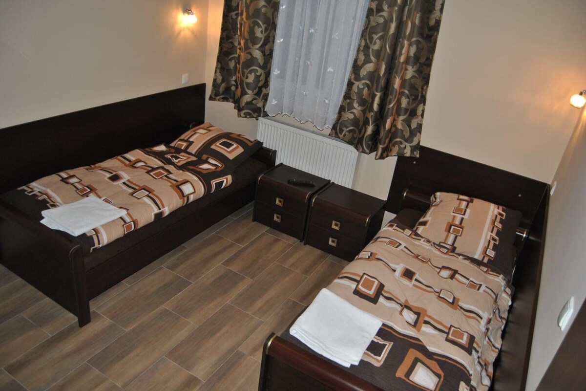 A small room with two beds, a dresser, and a radiator.