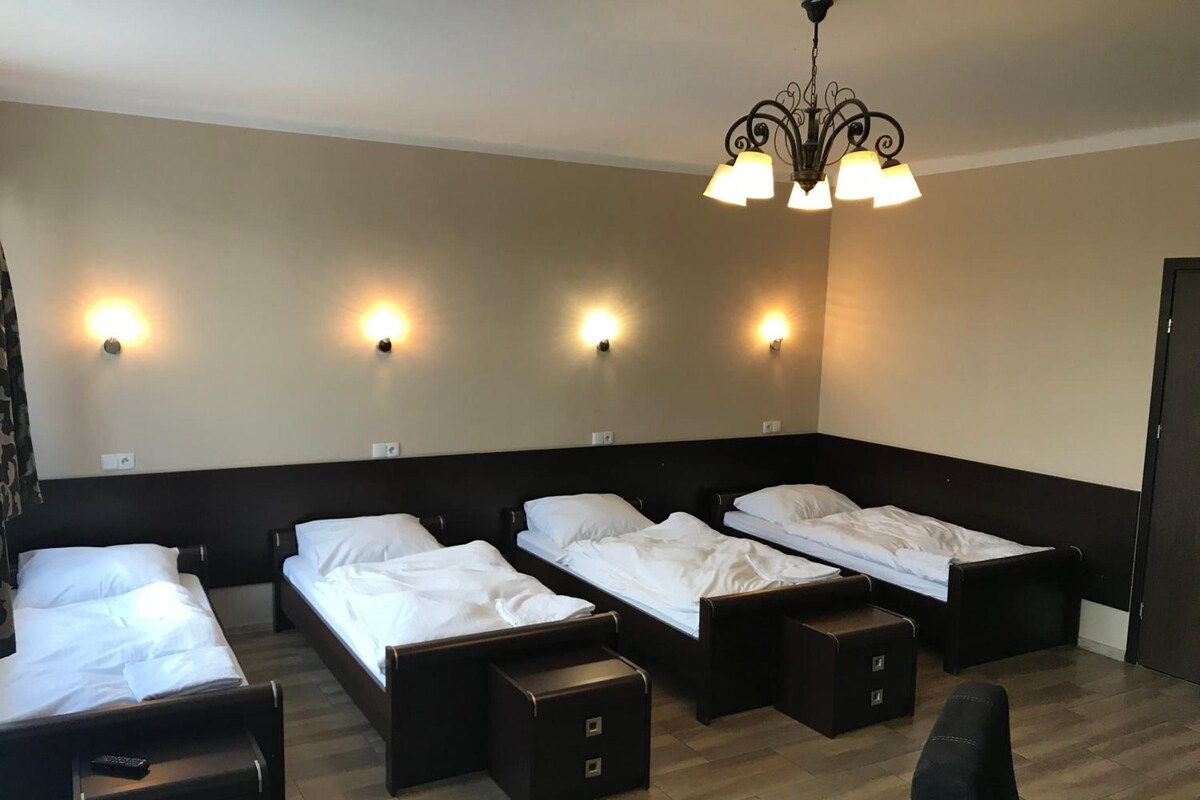 A hotel room with four single beds, a desk, and a chair.