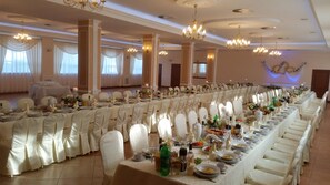 A banquet hall with long tables set for a formal event, featuring chandeliers and white drapery. - Hotel Go Ociniec (Wloclawek)