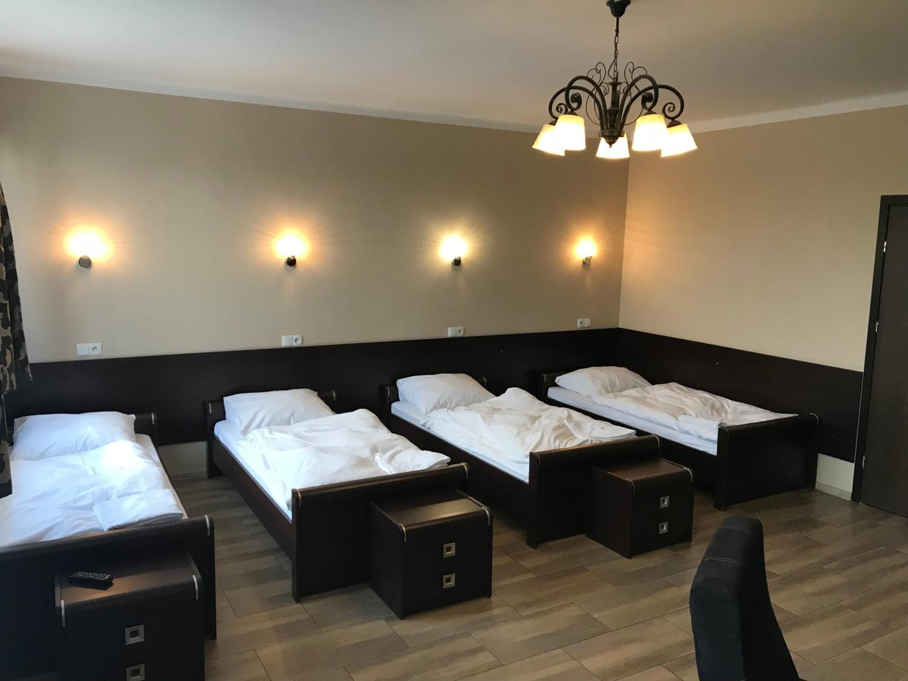 A hotel room with four single beds, a desk, and a chair.