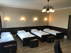 A hotel room with four single beds, a desk, and a chair.