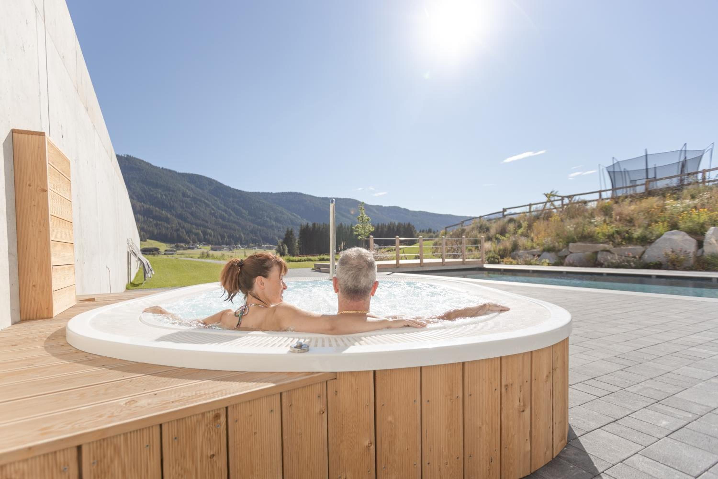 A hot tub with a wooden deck and a view of mountains in the background.