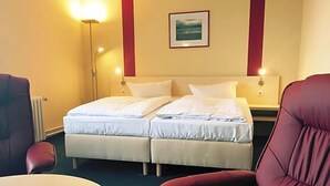 A hotel room with two beds, a desk, a chair, and a lamp. - Panorama Hotel Bansin (Heringsdorf)